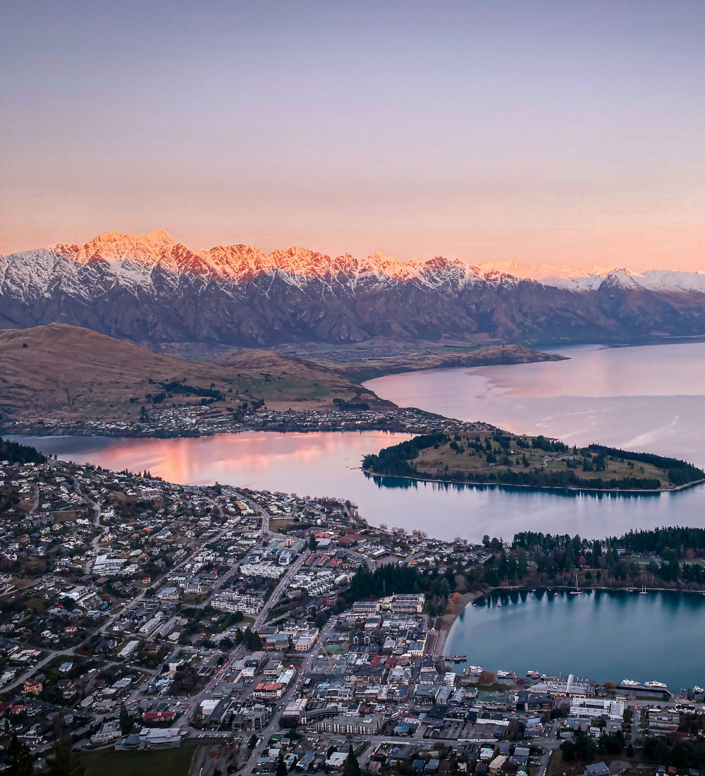 Thumbnail image. Image showcases Queenstown, Lake Wakatipu, and the Remarkables mountain range during what appears to be sunrise or sunset.